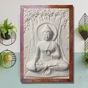 May include: A white, 3D relief sculpture of Buddha sitting in meditation under a tree. The sculpture is framed in a dark wood frame.