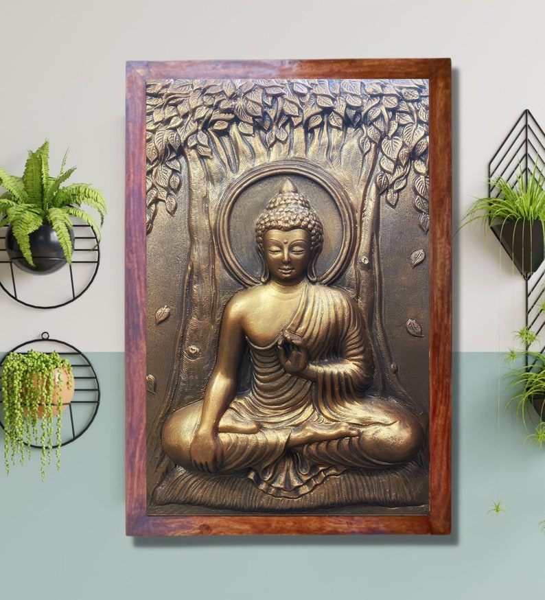 May include: A gold-colored Buddha statue in a wooden frame. The statue is sitting in a meditative pose with hands in the lap. The statue is surrounded by a tree with leaves.