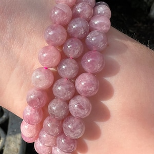 May include: A bracelet made of pink and white gemstone beads. The beads are round and have a smooth, polished finish.