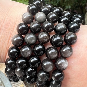 Peut inclure: Un bracelet composé de perles de pierres précieuses noires et grises. Les perles sont rondes et ont une finition lisse et polie.