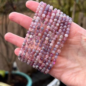 May include: A stack of purple and pink gemstone bracelets. The bracelets are made with small, round beads.