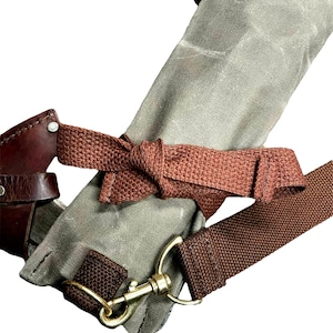 May include: A close-up of a brown leather and canvas bag with a brown strap and a brass clasp. The bag is tied with a brown strap.