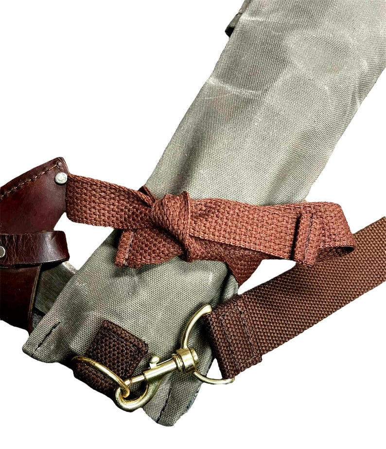 May include: A close-up of a brown leather and canvas bag with a brown strap and a brass clasp. The bag is tied with a brown strap.