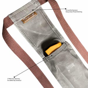 May include: A gray canvas saw holder with two brown straps. The holder has a 3-inch wide opening for added slip resistance. The straps are UV and rot resistant with heavy-duty thread stitching. The text "Campcraft" and "www.campcraftoutdoors.com" is printed on the holder.