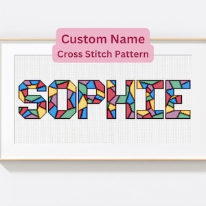 Puede incluir: Arte de punto de cruz enmarcado con el nombre "SOPHIE" en letras geométricas coloridas. El diseño incluye una pancarta rosa que dice "Custom Name Cross Stitch Pattern". La obra de arte se muestra en un marco blanco.