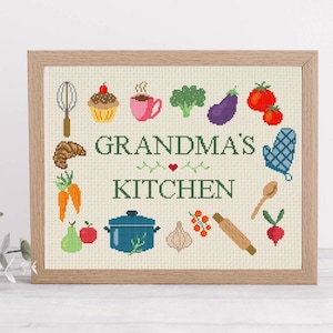 Op de afbeelding: Een ingelijst kruissteekontwerp met de tekst "Grandma's Kitchen" omringd door kleurrijke illustraties van voedsel en keukengerei. De lijst is lichtbruin en de achtergrond is crèmekleurig.