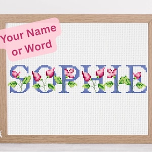 Könnte beinhalten: Kreuzstich-Kunstwerk in einem Holzrahmen. Das Wort "SOPHIE" ist in blauen Buchstaben gestickt, mit rosa Blumen und grünen Blättern. Ein pinkfarbener Haftzettel oben lautet "Your Name or Word".