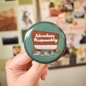 May include: A round, green button with the text "Adventure Responsibly" in white and brown. The button features a signpost design with the words "Creation Matters" below. The background is a collage of various images.