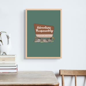 Puede incluir: Una impresión enmarcada verde con un letrero marrón que dice "Adventure Responsibly, Creation Matters". El letrero está rodeado de rocas y pequeñas flores.