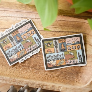 May include: Two illustrated stickers with a nature theme. The stickers are on a wooden surface. The text on the stickers reads "He placed eternity in our hearts".