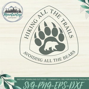 Pode incluir: Um design gráfico verde e branco com uma pegada de urso e um urso pequeno dentro da pegada. O texto ao redor da pegada diz "Hiking All The Trails Avoiding All The Bears".