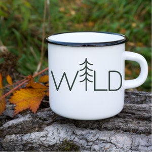 May include: White enamel mug with a black rim and a black and white graphic of a pine tree and the word "WILD".