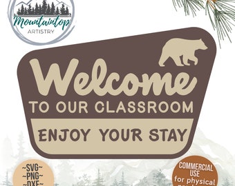 May include: A brown sign with rounded corners and a bear silhouette in the top right corner. The sign says "Welcome to our classroom Enjoy your stay". The sign is in front of a watercolour background of mountains and trees.