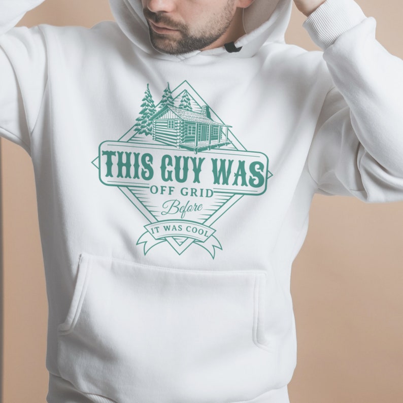May include: White hooded sweatshirt with a green graphic design of a cabin in the woods. The graphic says "This Guy Was Off Grid Before It Was Cool."