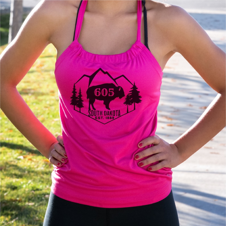 May include: Pink tank top with a black graphic of a buffalo, mountains, trees, and the text "605 South Dakota Est. 1889".