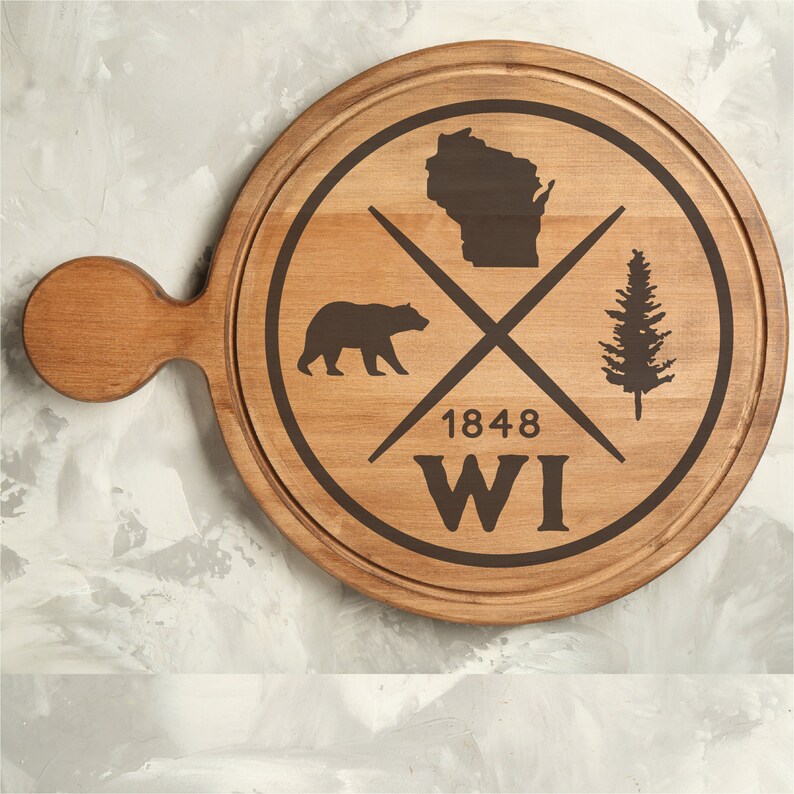 Pode incluir: Uma t&aacute;bua de servir de madeira com uma mancha marrom. A t&aacute;bua tem uma al&ccedil;a e um design circular com um urso, um pinheiro e o estado de Wisconsin. O design tamb&eacute;m inclui o texto "1848 WI".