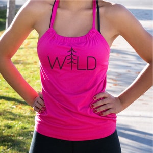 May include: A pink tank top with a black graphic of a pine tree and the word "WILD" printed on the front.