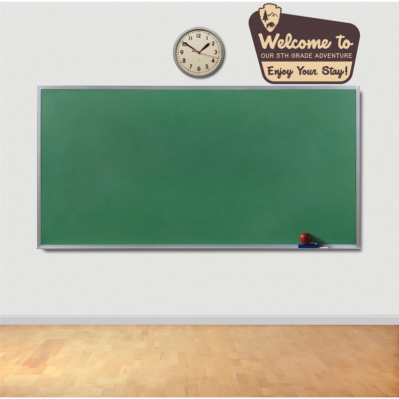 May include: A green chalkboard with a silver frame hangs on a white wall. A clock with black hands and a white face is above the chalkboard. A red apple and a white eraser are on the chalkboard. A brown sign with the text "Welcome to our 5th Grade Adventure Enjoy Your Stay!" is on the wall above the chalkboard.