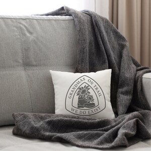 May include: White throw pillow with a gray graphic of a hiking boot with sunflowers and the text "Grandmas on Trail We Do Exist".