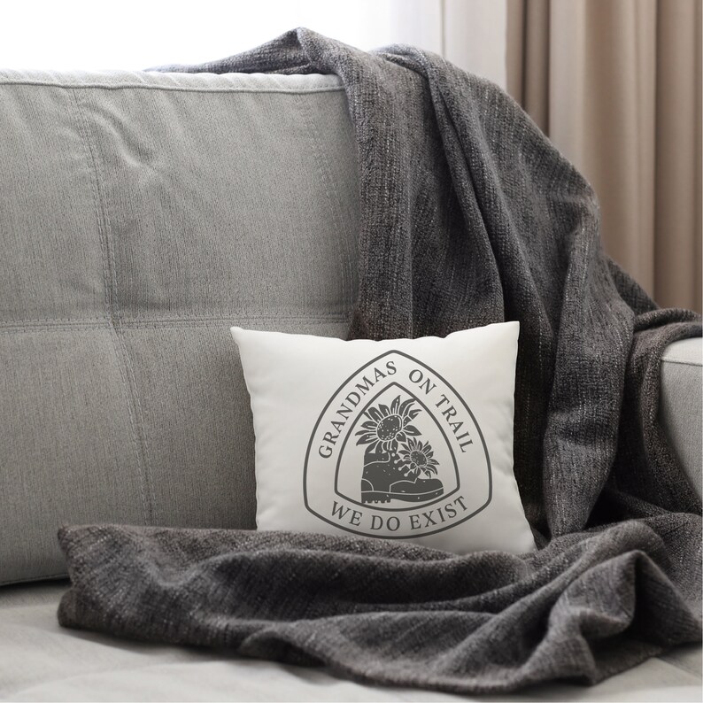 May include: White throw pillow with a gray graphic of a hiking boot with sunflowers and the text "Grandmas on Trail We Do Exist".