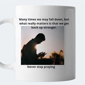 Puede incluir: Taza de cerámica blanca con la silueta de una persona mirando hacia abajo a su teléfono. La taza tiene el texto "Many times we may fall down, but what really matters is that we get back up stronger. Never stop praying." impreso en ella.