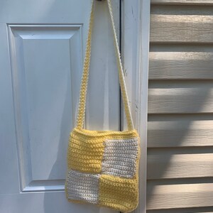 May include: A yellow and white crocheted shoulder bag with a checkered pattern.