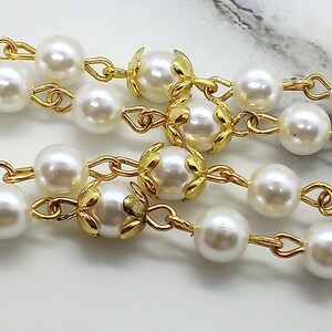 May include: A gold chain necklace with white pearl beads and gold leaf accents.