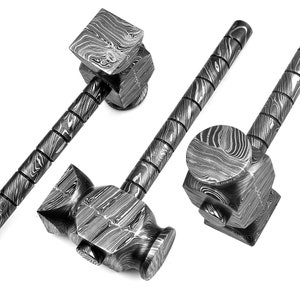 May include: Close-up of three Damascus steel hammers. The hammers have a patterned design in shades of gray and black. The handles are cylindrical with a series of rings. The hammer heads are square and rectangular.