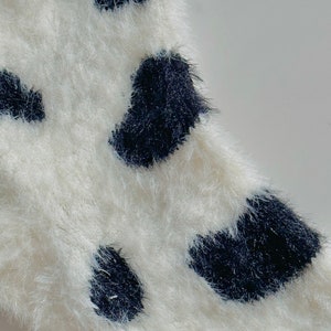 May include: White fuzzy fabric with black polka dots.