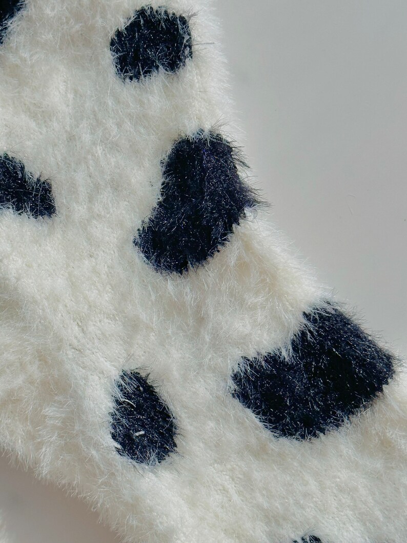 May include: White fuzzy fabric with black polka dots.