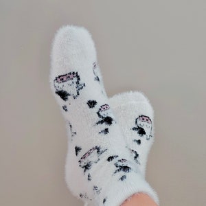 May include: White fuzzy socks with a black and pink cartoon design.