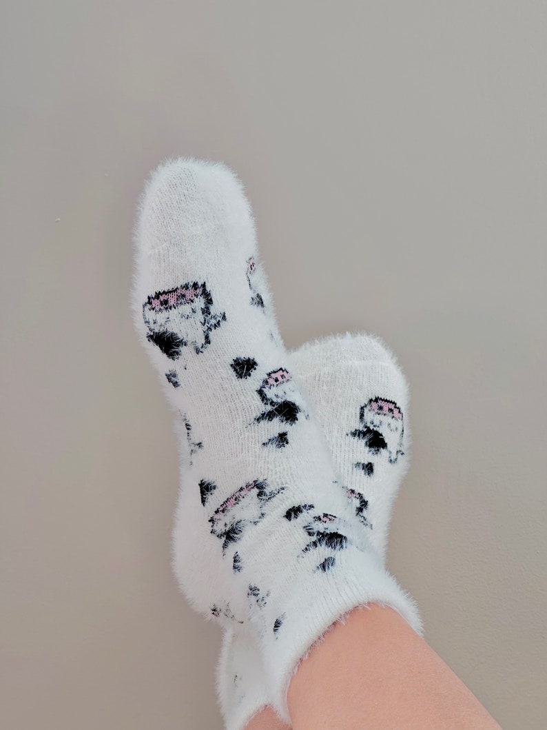 May include: White fuzzy socks with a black and pink cartoon design.