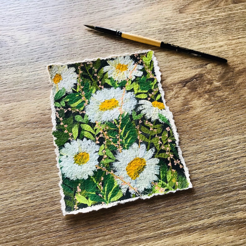 May include: A hand-painted watercolor illustration of a field of white daisies with yellow centers on a dark green background. The flowers are arranged in a random pattern and the edges of the paper are torn.