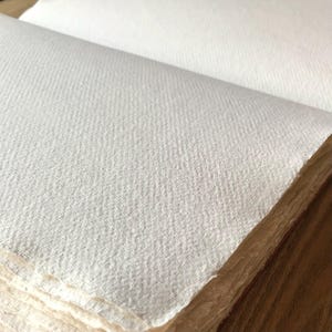 Pu&ograve; includere: Primo piano di una superficie di carta bianca testurizzata. La carta &egrave; piegata e ha una texture leggermente ruvida.