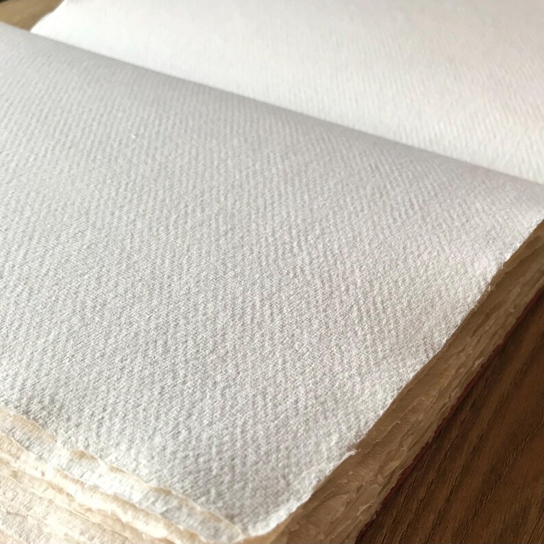 Pu&ograve; includere: Primo piano di una superficie di carta bianca testurizzata. La carta &egrave; piegata e ha una texture leggermente ruvida.