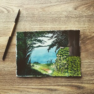 May include: Watercolor painting of a forest scene with a path leading to a lake. The trees are a dark green and the lake is a light blue. There are some small white flowers in the foreground.