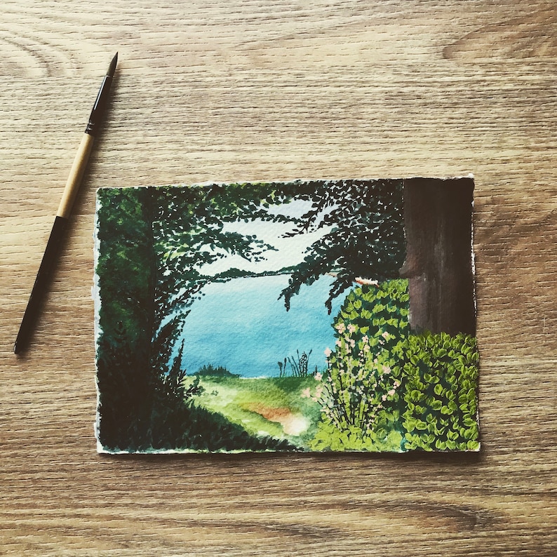 May include: Watercolor painting of a forest scene with a path leading to a lake. The trees are a dark green and the lake is a light blue. There are some small white flowers in the foreground.
