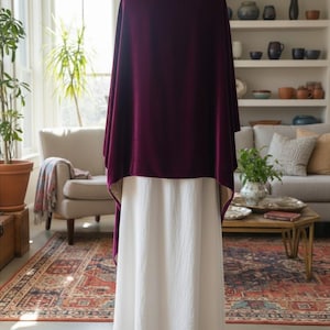 May include: A deep burgundy velvet shawl draped over a plain white floor-length skirt. The shawl features a smooth, rich texture and hangs loosely over the shoulders, while the skirt is made of a solid, opaque white fabric with a simple hemline.