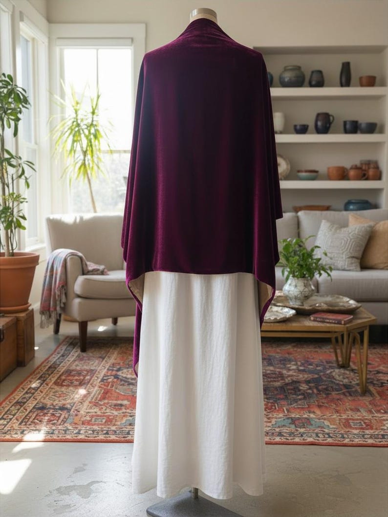May include: A deep burgundy velvet shawl draped over a plain white floor-length skirt. The shawl features a smooth, rich texture and hangs loosely over the shoulders, while the skirt is made of a solid, opaque white fabric with a simple hemline.