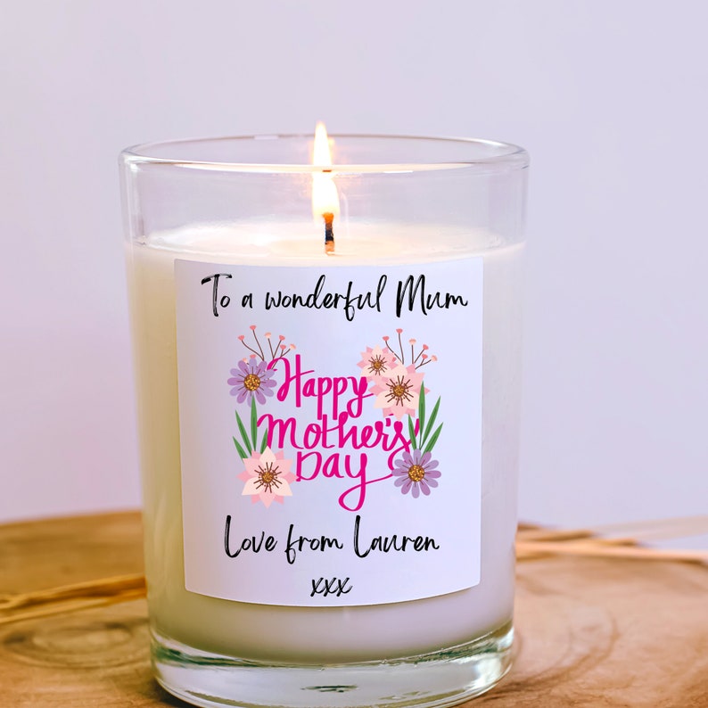 May include: A white candle with a pink and purple floral design label. The label reads "To a wonderful Mum Happy Mother's Day Love from Lauren xxx".
