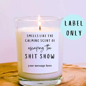 May include: White candle with a label that reads "Smells like the calming scent of escaping the shit show" and "your message here". The label is on a light blue background with the words "LABEL ONLY" in black.