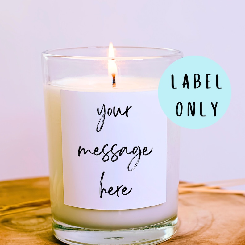 May include: A clear glass candle jar with a white label that says "your message here". The candle is lit and the flame is visible. The label is on a light blue background with the text "LABEL ONLY" in black.