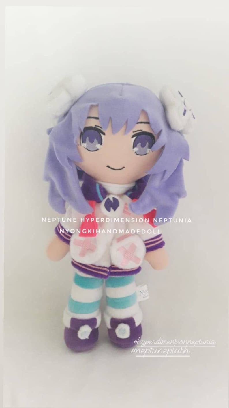 Puede incluir: Mu&ntilde;eca de peluche hecha a mano con cabello y ojos color lavanda. Viste un atuendo blanco y morado con leggings a rayas azules y blancas. El texto en la mu&ntilde;eca dice "NEPTUNE HYPERDIMENSION NEPTUNIA NYONGKIHANDMADEDOLL".