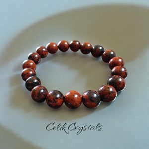 May include: Red and black gemstone bracelet with round beads.