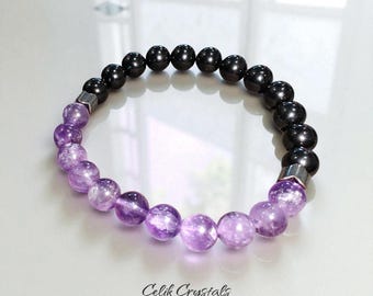 May include: A bracelet with alternating black and purple beads. The bracelet has a mix of black and purple beads, likely amethyst and hematite. The purple beads have a gradient effect. The text "Celik Crystals" is visible. The beads are approximately 1 cm in diameter.