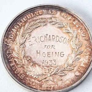 Może przedstawiać: Srebrny medal z motywem wieńca laurowego i tekstem "The Agricultural Society of Scotland E. Richardson for Hoeing 1933".