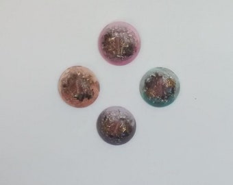 May include: Four round, flat, resin-filled, crystal-like objects with gold flecks. The objects are in shades of pink, purple, brown, and teal.