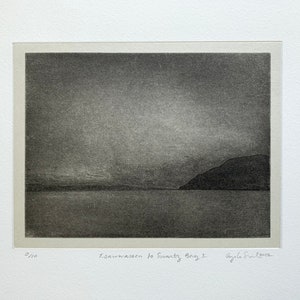 Puede incluir: Una impresión en blanco y negro de un paisaje con una cordillera en la distancia y una masa de agua en primer plano. La impresión está titulada "Isawwaasen to Svanth Bay 1" y está firmada por la artista, "Ayla S. Love".