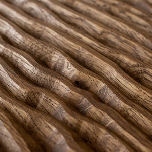 May include: Close-up of a wooden surface with a repeating wave pattern. The wood grain is visible, with variations in light and dark brown tones. The design creates a textured, three-dimensional effect.