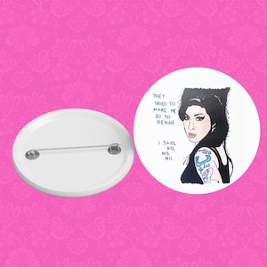 May include: A white button with a black and white illustration of Amy Winehouse. The text on the button reads "They tried to make me go to rehab. I said, no, no, no."